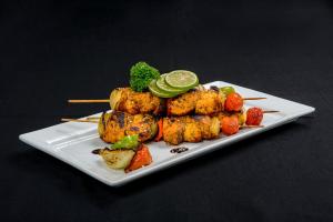 a plate of food with skewers of meat and vegetables at Gazelle International Hotel in Kokopo