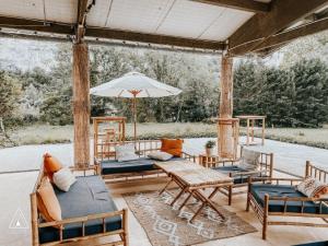 eine Terrasse mit Stühlen, Tischen und einem Sonnenschirm in der Unterkunft Lodg'ing Nature Camp Dordogne in Lacave