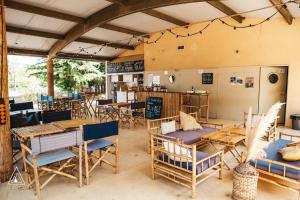 un restaurant avec des tables et des chaises en bois et une cuisine dans l'établissement Lodg'ing Nature Camp Dordogne, à Lacave