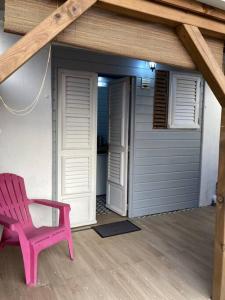 una silla rosa sentada en un porche con garaje en Agréable logement, bien situé en Schœlcher