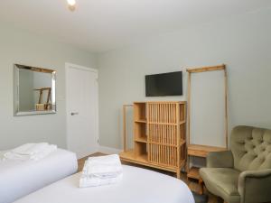 a room with a bed and a chair and a television at Birch House in Corsham