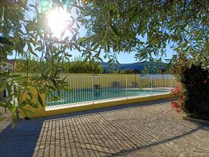 una cerca con el sol brillando a través de un árbol en Le Gîte de Marilou classé 3 étoiles Vallon Pont d'Arc, résidence privée piscine, en Vallon-Pont-dʼArc