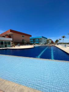 a swimming pool with a tile floor and a building at Golden Lake - 1 quarto in Arraial do Cabo
