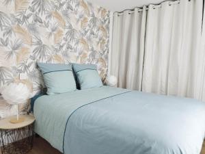 Saint-Michel-Mont-MercureにあるGîte de l'Archangeのベッドルーム1室(花柄の壁紙、青いシーツ付きのベッド1台付)