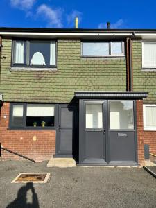 a brick house with a gray door and windows at Very comfy 3 bed town house in Ashton under Lyne