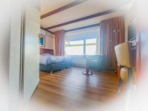 een hotelkamer met een bed, een bureau en een raam bij Hotel de Boegschroef in Delfzijl