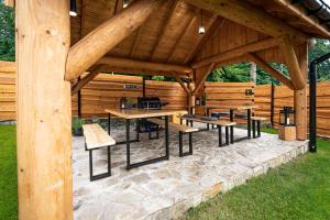 ウストロンにあるApartamenty w Lipowskiej Chacie - jacuzzi i saunaの庭にベンチとテーブルが置かれた木製のパビリオン