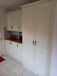 a kitchen with white cabinets and white tile floors at 13 Pearse Tce. in Sligo