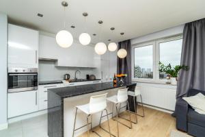 a kitchen with white cabinets and a bar with stools at Apartament Modern w Albatross Towers Gdańsk in Gdańsk