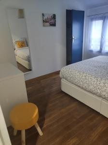 1 dormitorio con cama, taburete y espejo en Une Parenthèse Enchantée en Saint-Sébastien-sur-Loire