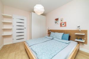 a bedroom with a bed with a wooden headboard at Apartament Modern w Albatross Towers Gdańsk in Gdańsk