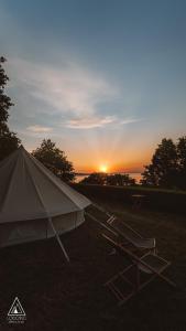 ein Zelt auf einem Feld mit Sonnenuntergang im Hintergrund in der Unterkunft Lodg'ing Nature Camp Presqu'île Crozon in Lanvéoc