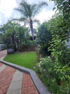 um jardim com um passadiço de tijolos e relva verde em Mistica on St James em Joanesburgo