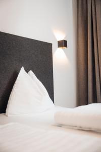 a bed with white sheets and a lamp on it at Hotel Gasthof Hirschentenne in Stams
