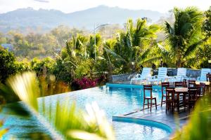 uma piscina de resort com cadeiras e mesas e montanhas ao fundo em KNN Luxury Hill em Sen Monorom