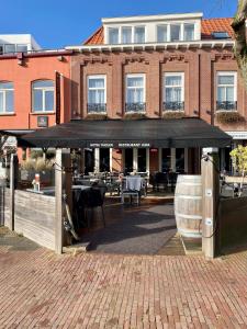 a restaurant with a black umbrella in front of a building at Hotel Tholen in Tholen