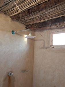 a bathroom with a shower with a light on the ceiling at Friendo's House & Hot Spring in Siwa