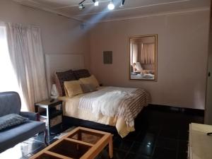 a bedroom with a bed and a mirror and a couch at Mosaic Guesthouse Welkom in Welkom