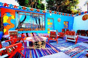um quarto azul com cadeiras coloridas e um tapete em Nubian studio em Aswan