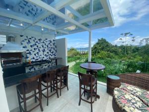 an outdoor kitchen with a table and chairs and a large window at Casa de praia in Paraty
