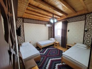 a room with two beds in a room with a rug at Khiva Siyovush Hotel in Khiva