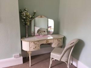 a dressing table with a mirror and a chair at Brook Lodge in Swanage