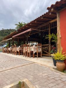 a restaurant with tables and chairs under a roof at Recanto da Roca in Domingos Martins
