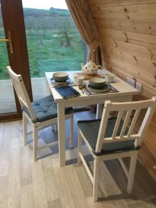 ダンガノンにあるOrchard Luxe Glamping Podのテーブル(椅子2脚付)、テーブル(ボウルと皿付)