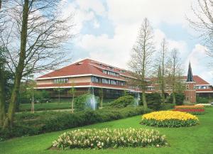 een gebouw met een bos bloemen ervoor bij Van der Valk Hotel Avifauna in Alphen aan den Rijn