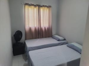 zwei Einzelbetten in einem Zimmer mit Fenster in der Unterkunft Casa proximo a praia in Paulista