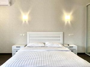 ein Schlafzimmer mit einem weißen Bett und zwei Nachttischen in der Unterkunft 2-кімн Просторі апартаменти ,світлий, стриманий дизайн in Poltawa
