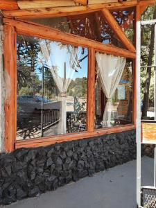 een raam van een huis met een stenen muur bij Ensueño del alma in Villa Pehuenia