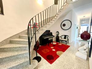 een trap met een piano en een rood tapijt bij Ta Phyllis - Apartments & Villas with Sunset & Sea Views in Għajnsielem