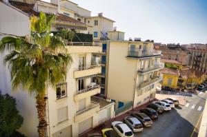 budynek mieszkalny z palmą i samochodami zaparkowanymi na ulicy w obiekcie Ref JUAS - Palmes d'Or Properties w Cannes