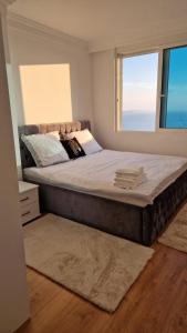 Una cama grande en un dormitorio con una ventana grande. en Pirro Luxury Apartment, en Sarandë