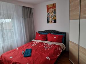 a bedroom with a red bed with a red comforter at Marya's in Râmnicu Vâlcea