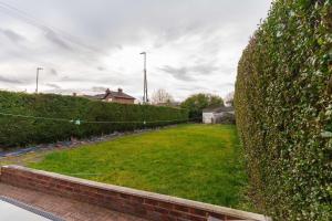 eine Hecke mit grünem Rasen im Hof in der Unterkunft OAKWOOD HOUSE Detached home in South Leeds in Leeds