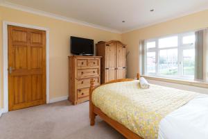 Schlafzimmer mit einem Bett, einem TV und einem Fenster in der Unterkunft OAKWOOD HOUSE Detached home in South Leeds in Leeds