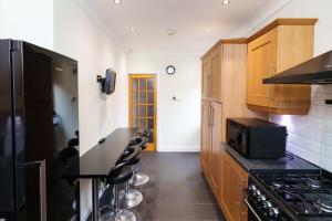 uma cozinha com armários de madeira e um micro-ondas preto em OAKWOOD HOUSE Detached home in South Leeds em Leeds