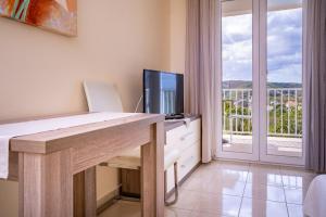 a room with a desk with a television and a balcony at Apartments Stare Brajde in Lopar