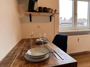 - une table en bois avec 2 assiettes et des verres à vin dans l'établissement Gemütlich Wohnen in der Neckarstadt, à Mannheim