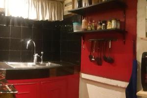 cocina con fregadero y pared roja en Billgren House, en Imus