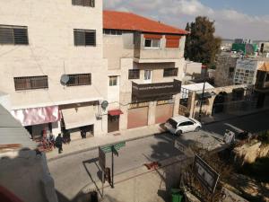 a white car parked on a street next to a building at Student House in Madaba