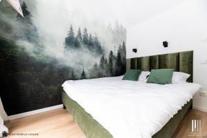 ein Schlafzimmer mit einem großen Bett und einem Waldbild in der Unterkunft Dolina Białej Wody - Domki w Karkonoszach in Jarkowice