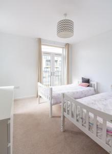 a white bedroom with two beds and a window at North London Suburbs in Barnet