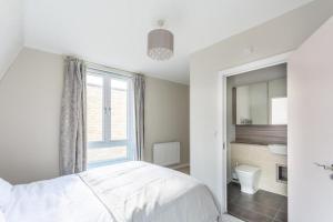 een witte slaapkamer met een bed en een raam bij North London Suburbs in Barnet