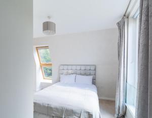 a white bedroom with a bed and a window at North London Suburbs in Barnet