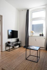 ein Wohnzimmer mit einem TV und einem Tisch in der Unterkunft FeelsLikeHome - Schöne&zentral angebundene Altbauwohnung mit Parkplatz in Bochum