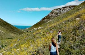 a group of people walking up a hill at Cottage in Voëlklip between mountain and sea in Hermanus