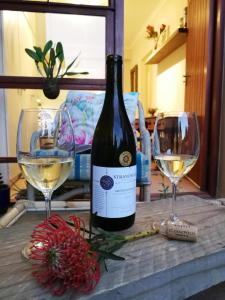 a bottle of wine and two glasses on a table at Cottage in Voëlklip between mountain and sea in Hermanus